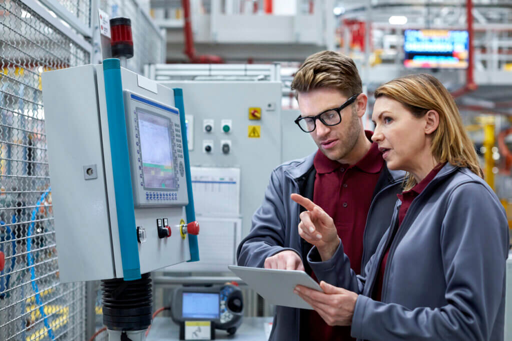 Image featuring colleagues working on a computer console in an advanced manufacturing setting.